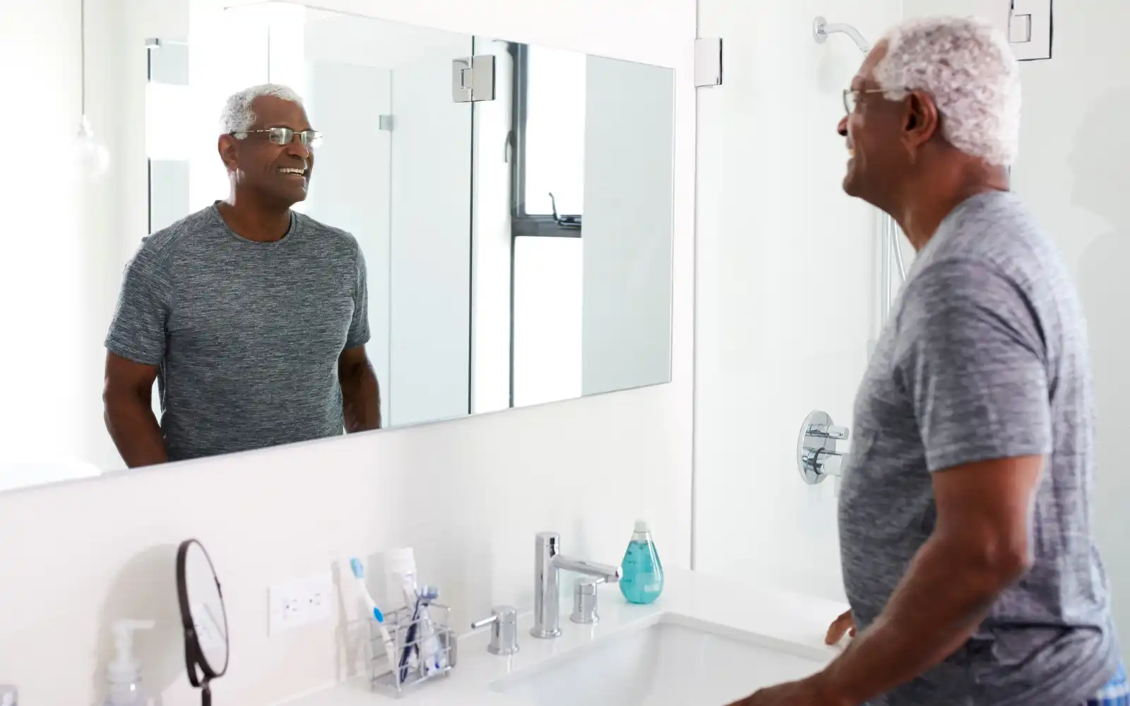 man-smiling-in-mirror-after-bathroom-fitters-prowess-developments-completed-the-job